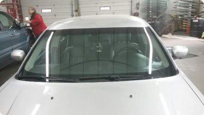 Silver sedan with a newly installed windshield in the service bay