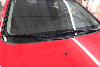 Red car with a new clear windshield parked in the Sidney Glass shop