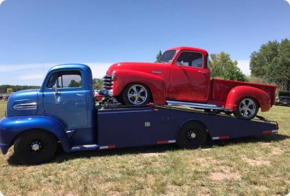 Restored red classic pickup truck loaded on a blue vintage car hauler