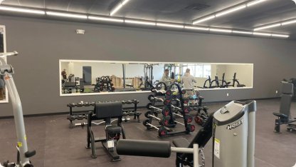 Long wall mirror installed in a bright gym with weight equipment