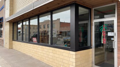 Wrap-around black storefront windows on a cream brick building