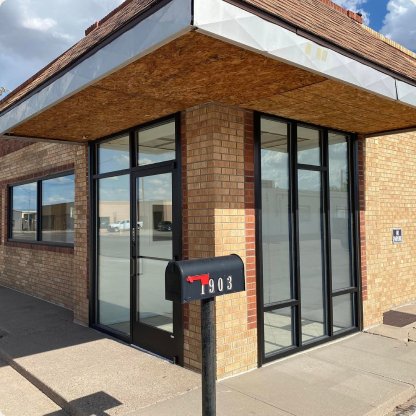 Brick corner building with new black-framed floor-to-ceiling storefront glass
