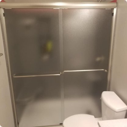 Frosted glass bypass shower doors with brushed frame in a bathroom